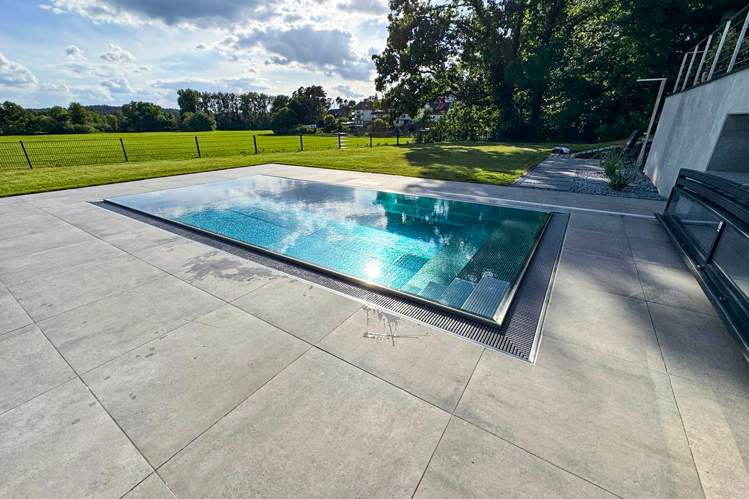 Edelstahl Schwimmbecken mit Überlauftechnik Edelstahlbecken mit Überlaufrinne, Treppe und freiem Blick in die Landschaft